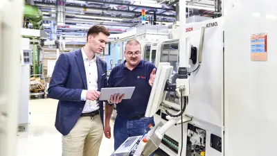 Bernhard Kohl shows Fabian Bucksch a defect on the grinding machine's monitor.